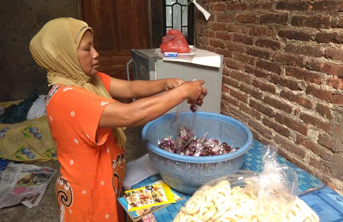 Siti Khotijah saat mengemas madu mongso dan arak keling, jajanan hasil olahan tangannya.