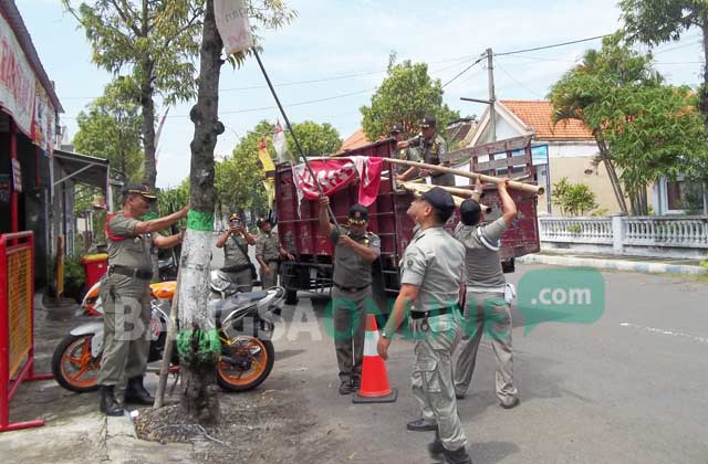Anggota Satpol PP Kab Nganjuk, saat membredeli spanduk yang tidak memiliki izin. foto: BAMBANG DJ/ BANGSAONLINE