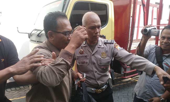 Tersangka Kades Gempolsari Kecamatan Tanggulangin Abdul Haris (45) menutupi wajahnya menghindari kejaran wartawan saat hendak dibawa menuju Lapas Sidoarjo, kemarin. foto: nanang ichwan/ BANGSAONLINE