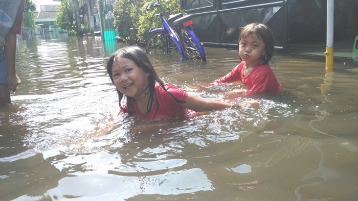 Banjir di wilayah Perumahan Gempol  Asri yang dimanfaatkan anak-anak perumahan bermain air. Foto: SUPARDI/BANGSAONLINE