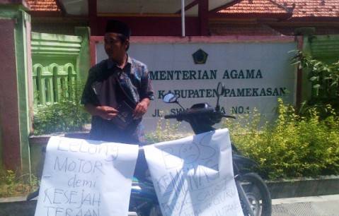 Kepala Sekolah MI Taufiqus Sibyan, Ach Fakih dengan motor yang dilelang. Foto: rizal/BANGSAONLINE