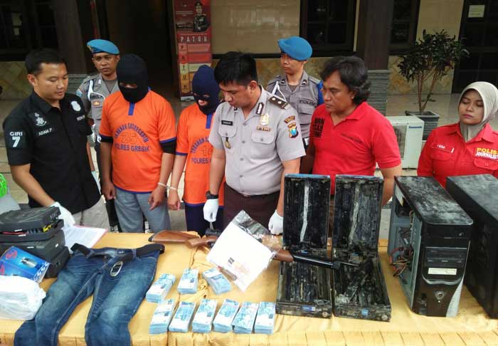 Kasat Reskrim Polres Gresik AKP Adam Purbantoro saat mengekspos kedua tersangka pembobol ATM BNI beserta hasil jarahannya. foto: SYUHUD/ BANGSAONLINE