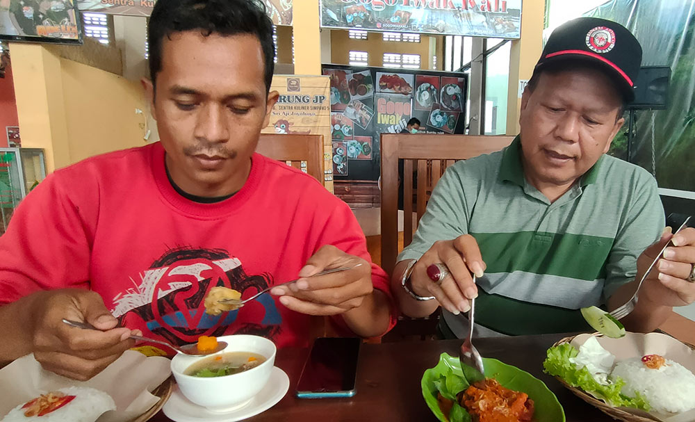 Mesakh Kusdianto dan Sutrisno, pengunjung Kedai Gogo Iwak Kali saat menikmati menu masakan sop kutuk dan rica-rica kutuk. foto: MUJI HARJITA/ BANGSAONLINE