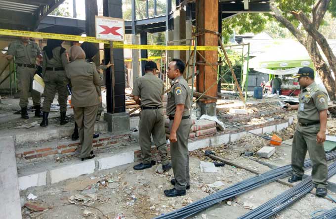 Petugas saat memasang garis tanda segel di bangunan milik Sudarmi di GKB. foto: SYUHUD/ BANGSAONLINE