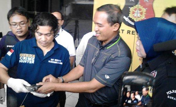 Tersangka Eko Harijadi, saat memberikan senjata yang digunakannya untuk menodong ke Kasatreskrim Polrestabes Surabaya AKBP Takdir Matanette. foto: ekoyono/ BANGSAONLINE