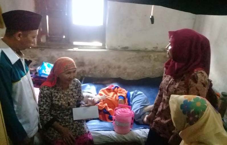 Fatimah (tengah) terbaring di kasur didampingi neneknya saat mendapatkan bantuan swadaya.