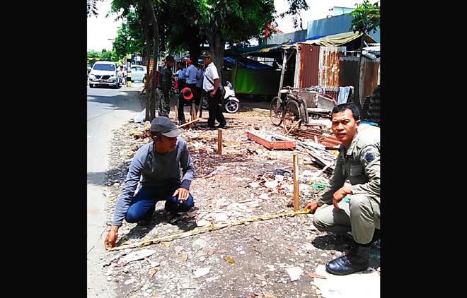 Petugas gabungan Satpol PP dan kepolisian ketika menertibkan PKL di kanan kiri Jalan Siti  Fatimah Binti Maimun. foto: SYUHUD/ BANGSAONLINE