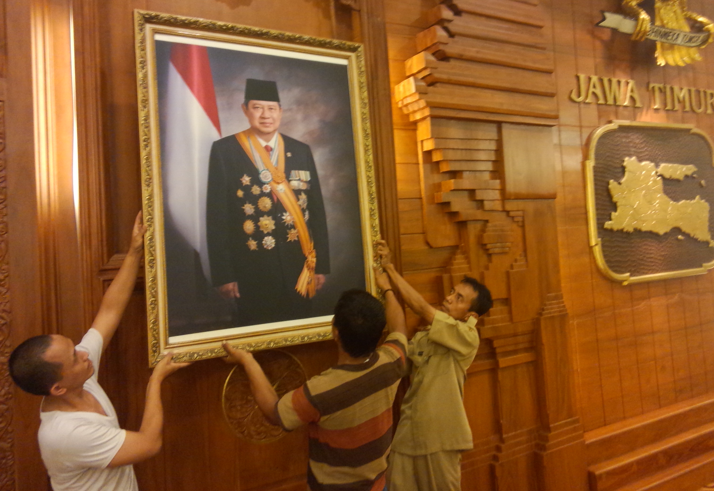 DITURUNKAN. Petugas di Grahadi menurunkan foto mantan presiden SBY. foto : nisa/bangsaonline