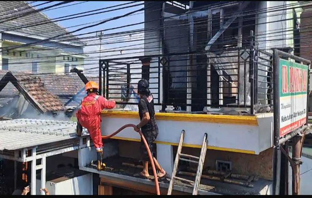 Petugas damkar saat berjibaku memadamkan api yang melalap salah satu rumah di Desa Karangagung.