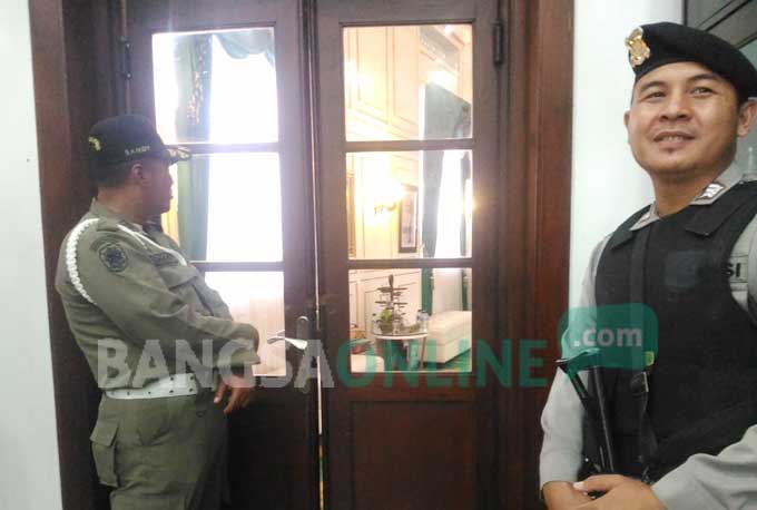 Petugas dari Satpol PP dan Polres Malang Kota sedang melakukan penjagaan di pintu masuk ruang kerja Wali  Kota Malang HM. Anton. foto: IWAN IRAWAN/ BANGSAONLINE