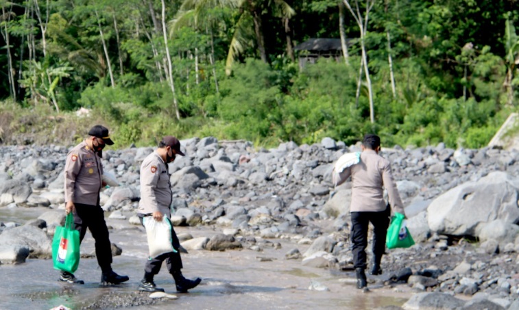 Kapolres Lumajang saat menuju lokasi pembagian sembako yang harus menyeberangi sungai.