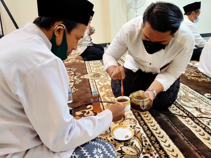 Santri Prof. Dr. KH. Asep Saifuddin Chalim, M.A., meneteskan madu kepada Ustad Karno, salah seorang peserta salat malam di kediaman Ning Imah di lingkungan Pondok Pesantren Amanatul Ummah Surabaya tadi malam, Kamis (15/7/2021). foto: mma/ bangsaonline.com