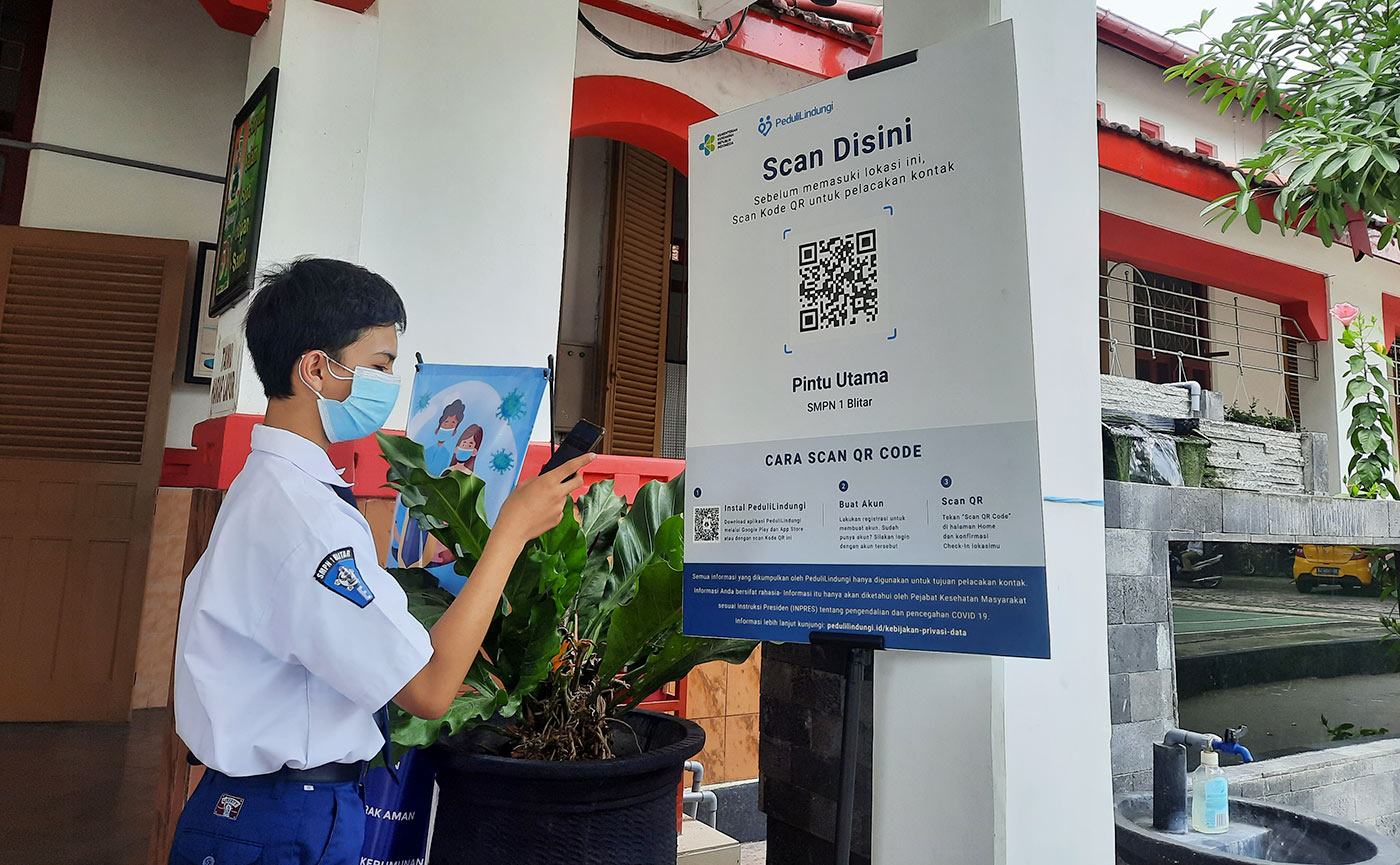 Seorang siswa melakukan scan barcode Aplikasi PeduliLindungi.