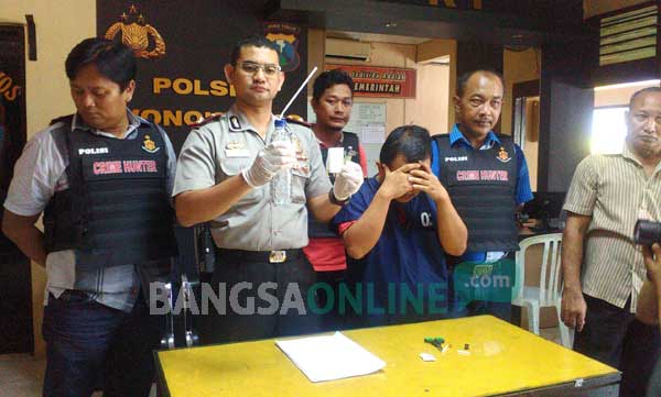 Tersangka Yudha didampingi Kapolsek Wonokromo. foto: ekoyono/ BANGSAONLINE