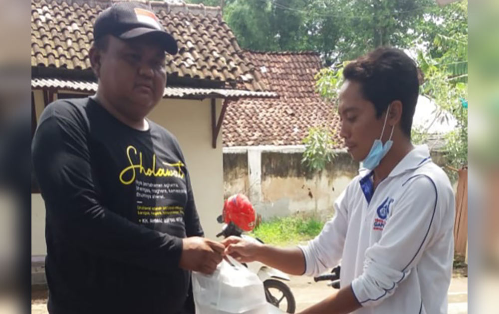 Salah satu relawan PKB Situbondo saat menyerahkan nasi bungkus kepada salah satu korban puting beliung. 
