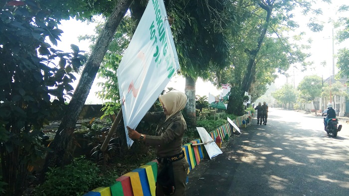 Petugas saat membersihkan ratusan banner di Jalan Hayam Wuruk. Foto: YUDI EP/BANGSAONLINE
