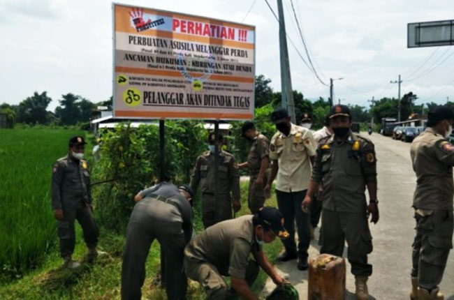 Petugas Satpol PP Kabupaten Mojokerto ketika menyegel dan memasang banner larangan praktek prostitusi di lokasi.