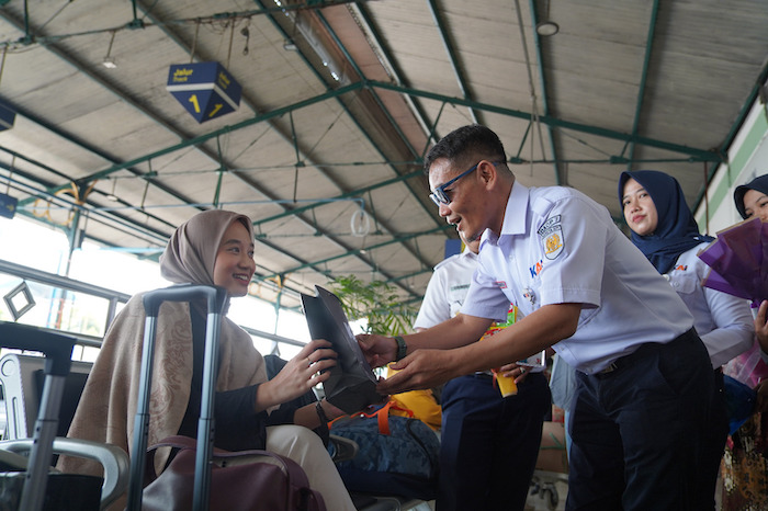 Petugas Daop 7 Madiun membagikan buket kepada pelanggan wanita.