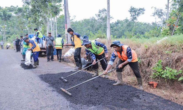 Petugas saat memperbaiki jalanan rusak di Jember