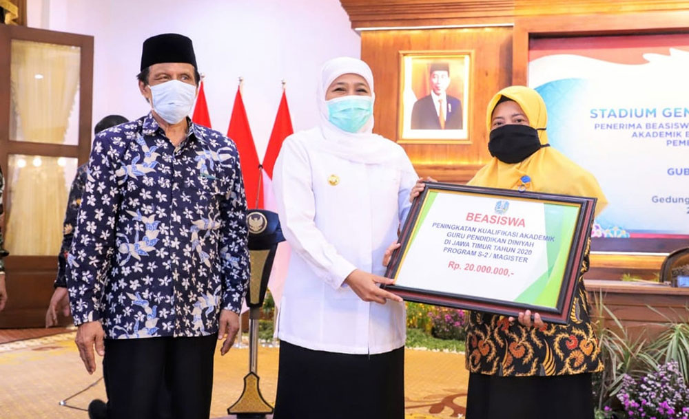 Gubernur Jatim Khofifah Indar Parawansa didampingi Kepala Biro Kesejahteraan Rakyat Pemprov Jatim Gatot Subroto saat menyerahkan beasiswa untuk guru madin secara simbolis.