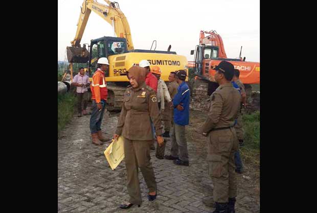 Petugas Dispol PP Gresik saat menghentikan pemasangan pipa Pertamina Gas di Desa Kedanyang Kebomas. foto: SYUHUD/ BANGSAONLINE