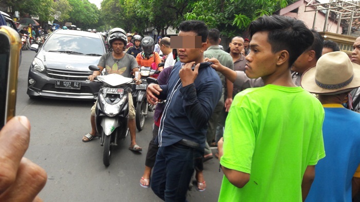 Tersangka Agus saat diamankan petugas Polsek Kebomas dari amukan massa. Foto: SYUHUD A/BANGSAONLINE