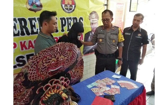 Pelaku (diapit petugas) bersama barang bukti berupa uang palsu.