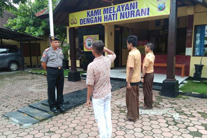 Tiga pelajar saat hormat kepada Merah Putih didampingi Kapolsek Senori AKP Kusrin. foto: AHMAD/ BANGSAONLINE
