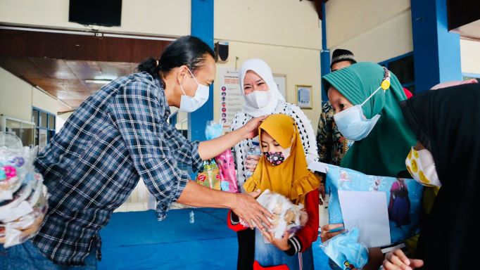 Dr Meithiana Indrasari, S.T., M.M. dan M Zurqoni menyerahkan sandal kepada para anak yatim dan dhuafa di Pendopo Stikosa-AWS Surabaya, Jumat (15/10/2021). foto: ist