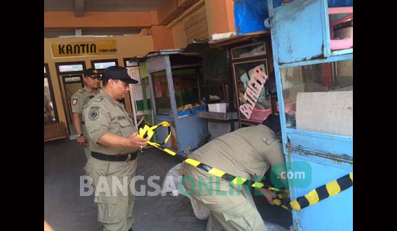 Petugas Satpol PP saat menyegel dengan memberi garis pengaman di sejumlah rombong milik PKL yang dirazia. foto : arif kurniawan/ BANGSAONLINE