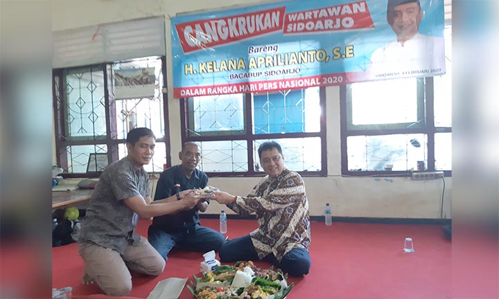 TUMPENG HPN: Kelana memberikan potongan tumpeng kepada perwakilan wartawan Sidoarjo, Selasa (4/2). foto: MUSTAIN/ BANGSAONLINE