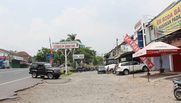 Kondisi ruko di kompleks Pandaan yang kurang terawat, jalan berlubang, dan bangunan tampak kusam.