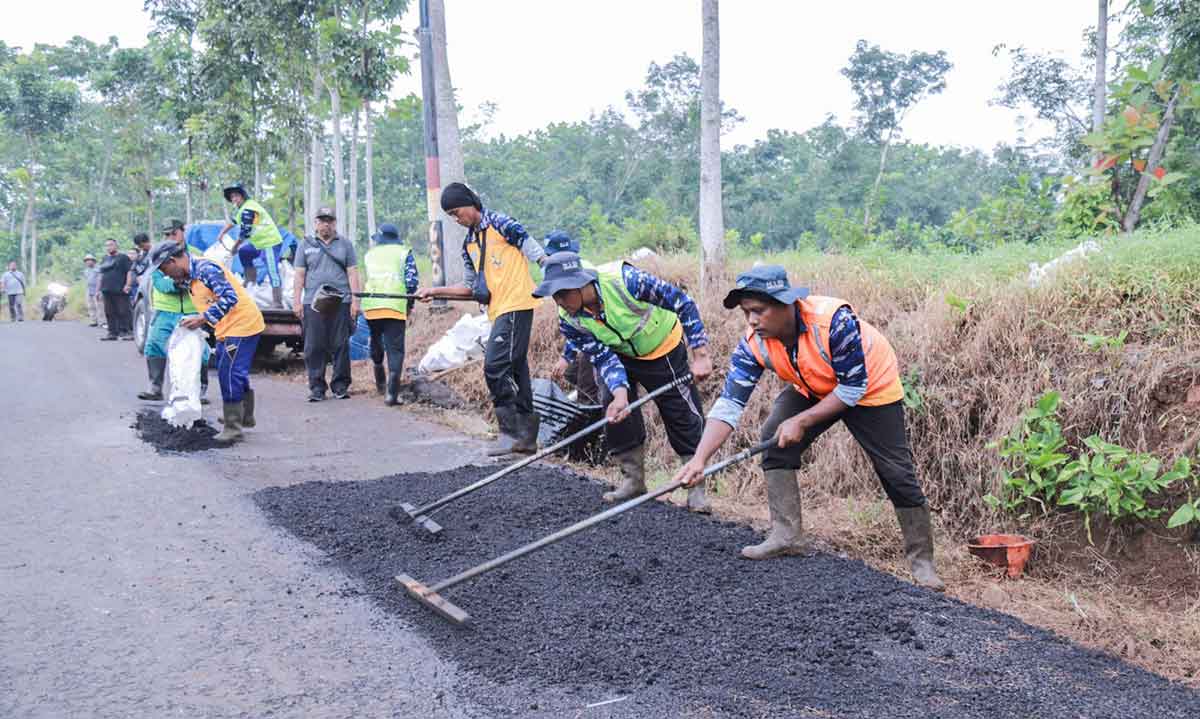 Petugas saat memperbaiki jalan rusak di Jember.
