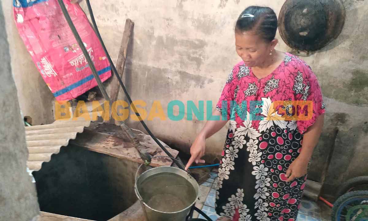 Sulastri, warga RT 5 RW 2 Kelurahan Tempurejo saat menunjukkan air sumur miliknya yang diduga tercemar BBM. Foto: MUJI HARJITA/ BANGSAONLINE