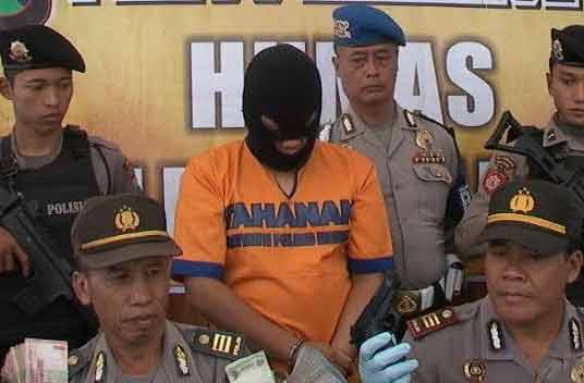 RILIS – Polisi menunjukkan tersangka perampokan minimarket memakai pistol mainan. (foto: detik)