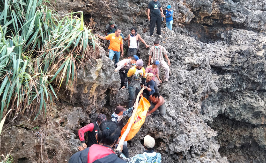 Warga membantu petugas mengevakuasi jasad korban dari tebing karang.