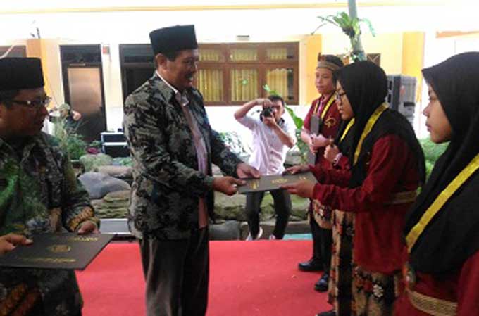 Kepala Kanwil Kemenag Jatim Drs. H. Syamsul Bahri, M.Pdi saat menyerahkan penghargaan kepada siswa/i terbaik di acara wisuda, Senin (28/05). foto: IWAN/ BANGSAONLINE