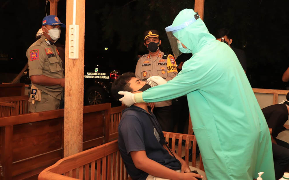 Petugas melakukan swab antigen terhadap salah satu pengunjung cafe yang melanggar jam malam.