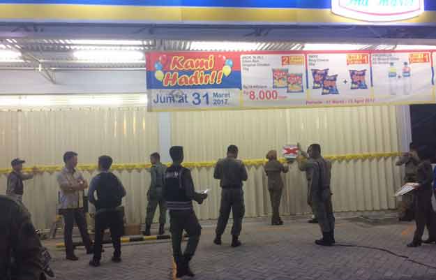 Petugas Dinas Satpol PP Pemkab Gresik saat menyegel Indomaret di Desa Kedanyang. foto: SYUHUD/ BANGSAONLINE
