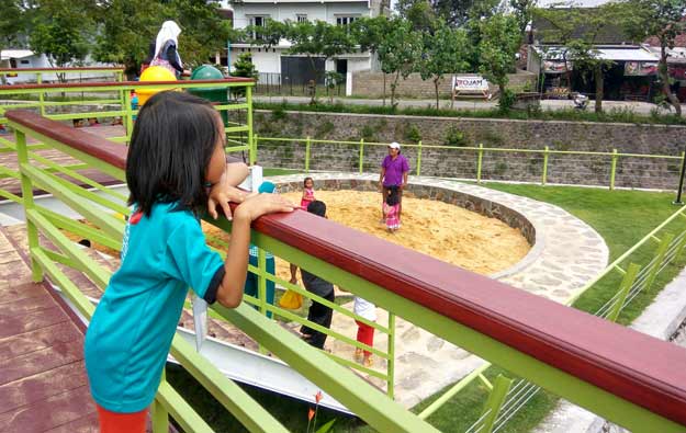 Masyarakat menikmati air sungai buatan yang mengalir disepanjang Taman Hijau SLG.