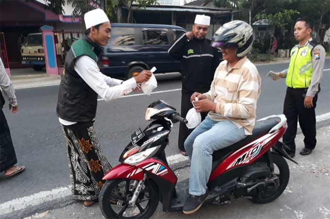 Grup hadrah AMB dan Syekher Mania Bojonegoro saat membagikan takjil kepada pengguna jalan.