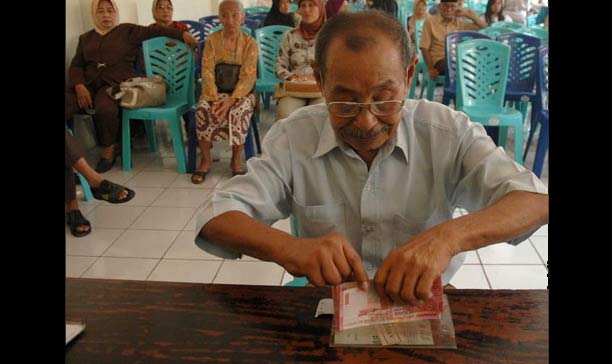 Seorang pensiunan sedang menghitung uang pensiunan yang diterima tiap bulan. Lebaran kali ini, mereka tidak mendapat THR.