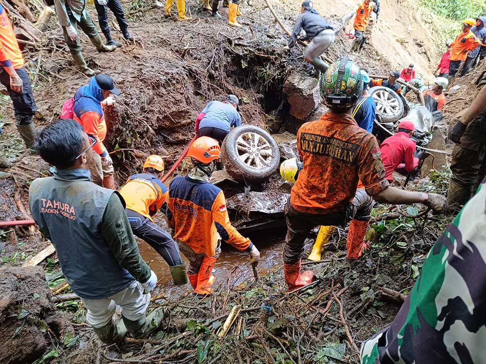 Tim penyelamat saat evakuasi satu unit mobil yang jatuh di jurang akibat tanah longsor di jalan alternatif Kota Batu-Pacet. (Ist)