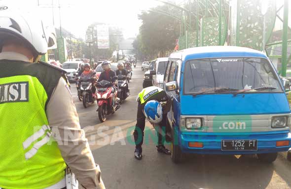 Petugas saat menggembosi salah satu ban mobil yang parkir di atas jembatan kampung putih, Kamis (20/07). foto: IWAN IRAWAN/ BANGSAONLINE