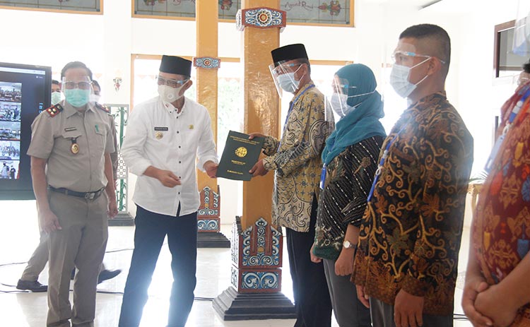 Budi Sulistyono, Bupati Ngawi menyerahkan sertifikat tanah secara simbolis kepada salah satu warga.