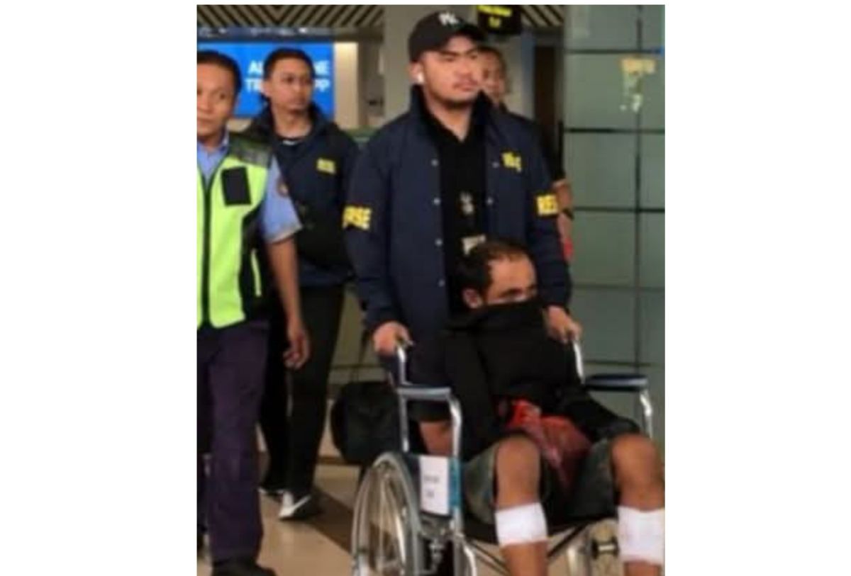 DPO Midhol duduk di kursi roda dengan kedua betis  tertembak didorong petugas di bandara dengan pengawalan ketat. FOTO: ist.