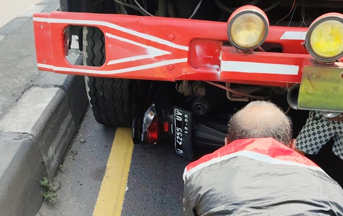 Kondisi sepeda motor masih terjepit di bawah kolong dump truk.