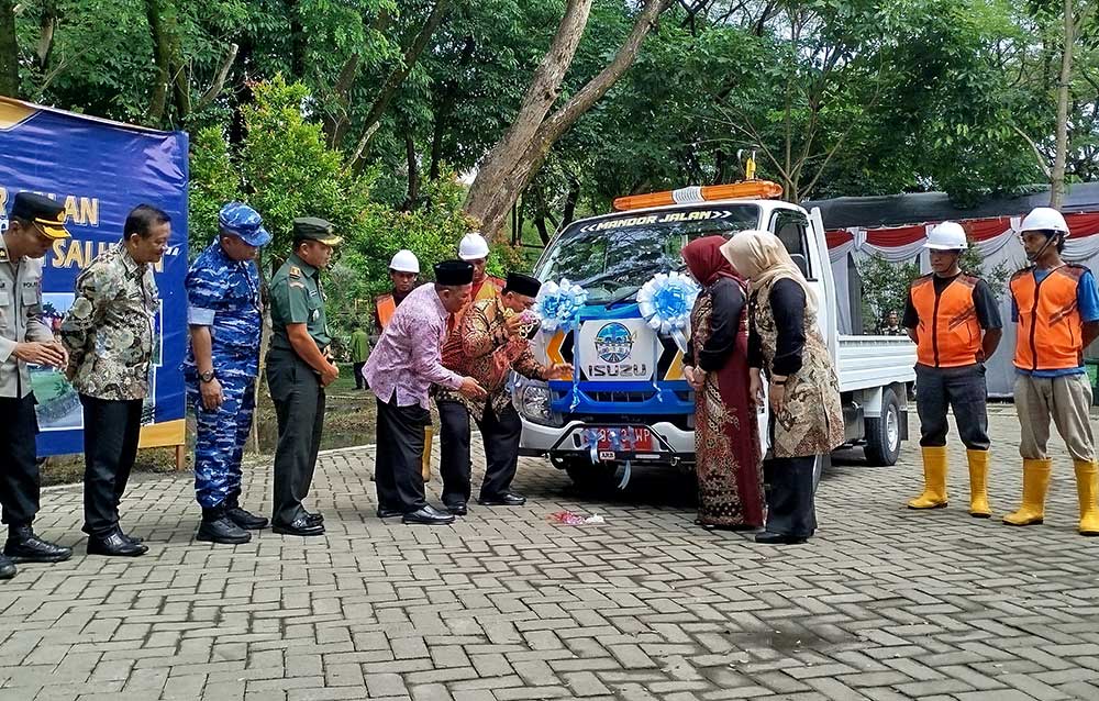 Bupati Jombang Warsubi saat melaunching tim mandor jalan dan normalisasi saluran ditandai dengan penyiraman air kembang pada armada yang digunakan. Foto: AAN AMRULLOH/ BANGSAONLINE