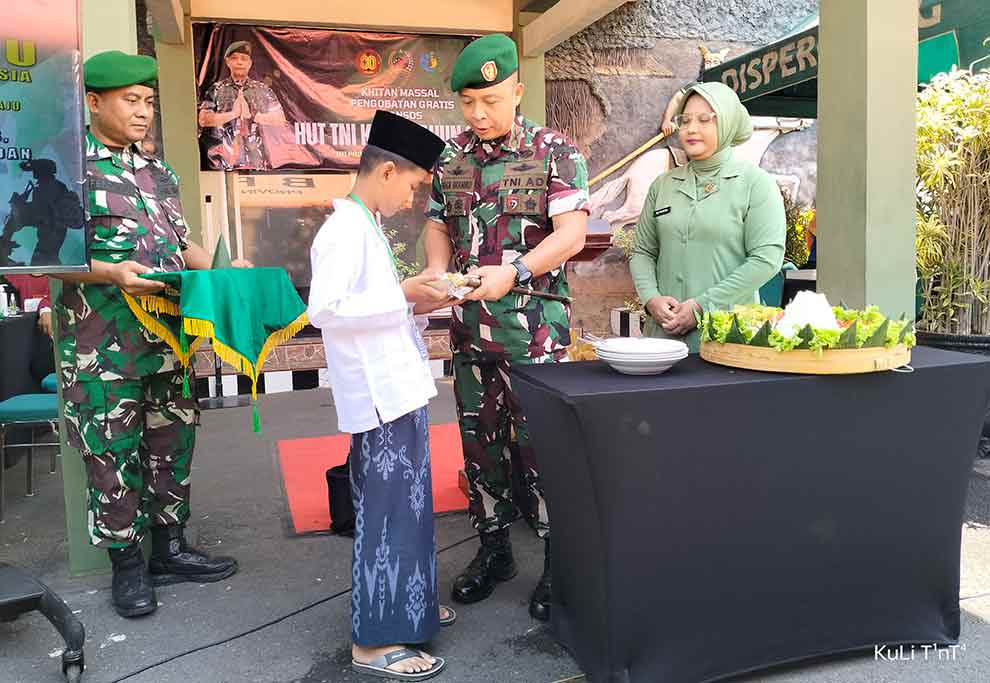 Komandan Kodim 0819 Pasuruan, Letkol Inf Boga Bramiko, didampingi Ketua Ibu Persit Ny. Vita Boga Bramiko saat memberikan potongan tumpeng ke salah satu peserta khitan.