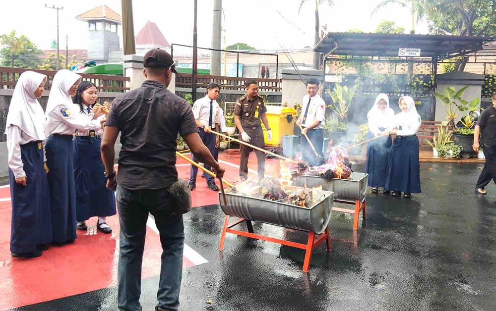 Para siswa SMPN 1 Tuban bersama petugas dari Kejari Tuban saat mengikuti pemusnahan barang bukti yang sudah inkrah.